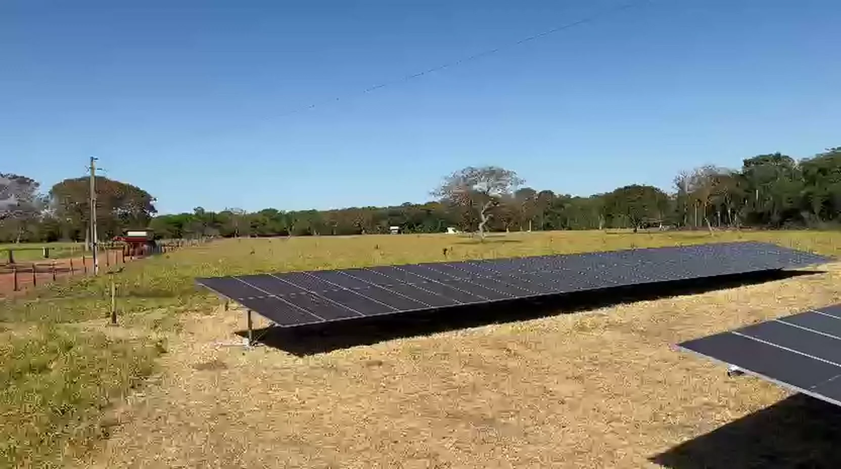 Fileira longa de módulos solares instalados em pasto, em propriedade rural atendida pela Mais Sol