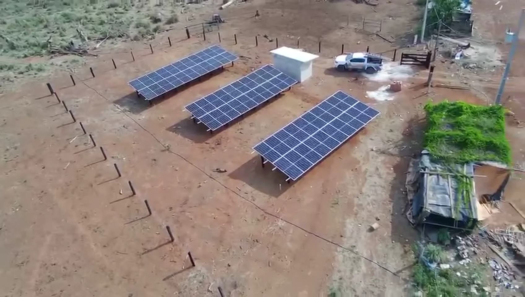 Três fileiras de módulos solares instaladas em sítio, com a caminhonete da equipe Mais Sol ao lado
